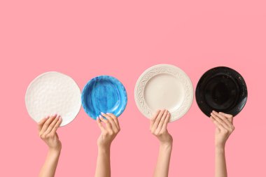 Pembe arka planda boş tabakları tutan eller