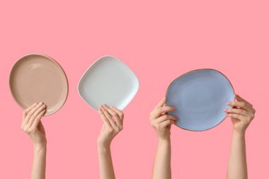 Pembe arka planda boş tabakları tutan eller