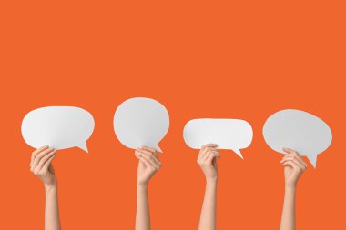 Turuncu arka planda konuşma baloncukları olan kadın eller