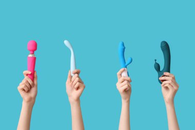 Mavi arka planda farklı vibratörlere sahip kadın elleri.