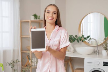 Banyoda tablet bilgisayarı olan genç bir kadın.