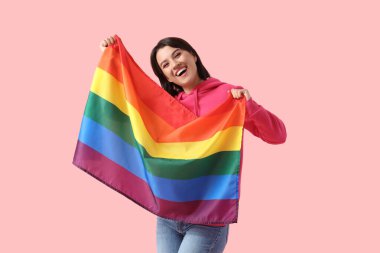 Pembe arka planda LGBT bayrağı olan mutlu genç bir kadın.