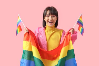 Pembe arka planda LGBT bayrağı olan mutlu genç bir kadın.