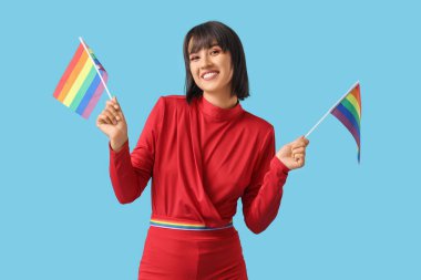 Beautiful young woman with LGBT flags on blue background