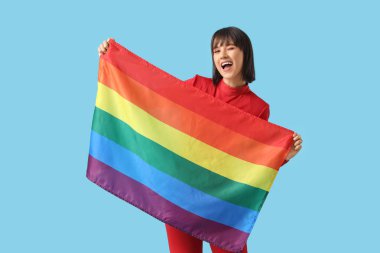 Beautiful young woman with LGBT flag on blue background