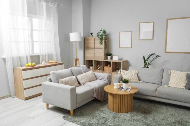 Gri kanepeleri, ahşap sehpası ve çiçekleri olan şık bir oturma odası.