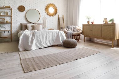 Yatak odasının penceresinin yanındaki yastıklı ve çekmeceli yumuşak bir yatak.