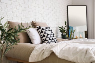 Rahat yatak, ev çiçekleri ve ayna şık bir yatak odasında.