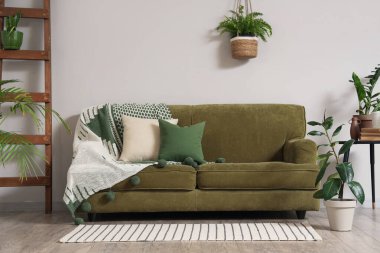 Oturma odasının içinde kanepe, merdiven, masa ve beyaz duvarın yanında farklı bitkiler var.