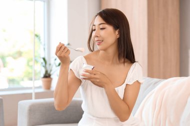 Evde lezzetli yoğurt yiyen güzel bir Asyalı kadın.