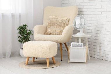 Oturma odasındaki çekmecelerin raflarında modern elektrikli vantilatörler var.