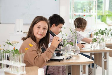 Biyoloji sınıfında mikroskobu olan genç bir kız.