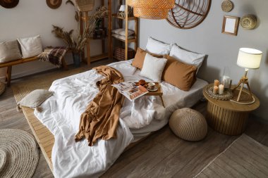 Şık bir yatak odası, rahat bir yatak odası, tepsi masası ve yanan mumlar.