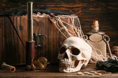 Gözlüklü kafatası, pusula ve paralar ahşap masada. Korsan konsepti