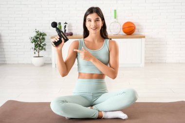 Spor salonunda vurmalı masaj aleti olan genç bir kadın.