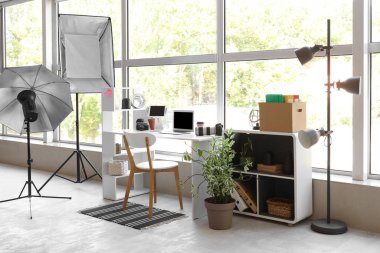 Modern stüdyoda dizüstü bilgisayarı, fotoğraf makineleri ve ışıklandırma ekipmanları olan fotoğrafçı işyeri