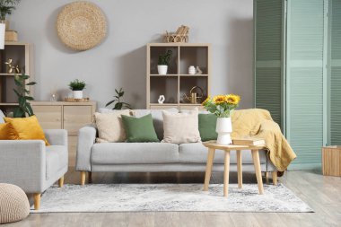 Kahve masasında gri kanepeler ve ayçiçekleri olan şık bir oturma odası.