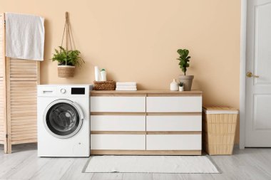 Modern çamaşır makinesi, şifonyer ve sepeti olan ev çamaşırhanesi.