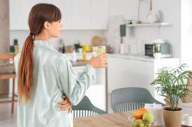 Yemek odasında bir bardak limon suyu olan genç bir kadın.