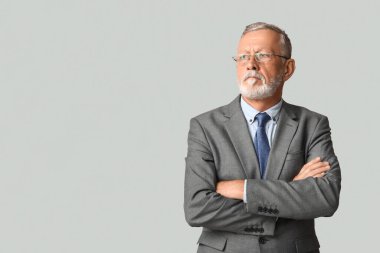 Gri arka planda kravatı olan şık takım elbiseli yakışıklı olgun bir adam.