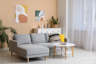 Rahat bir kanepe, kahve masası ve oturma odasındaki bej duvarda asılı bir resim.