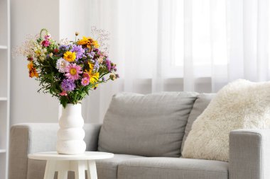 Oturma odasındaki sehpanın üzerinde yabani çiçekler olan vazo.