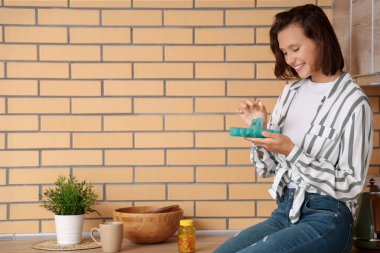 Mutfakta ilaç organizatörü olan güzel genç bir kadın.