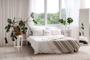 Işıl ışıl yatak odasının içi rahat yatak odası ve canavar yapraklarıyla dolu.