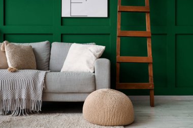 Gri kanepeli, puf ve ahşap merdivenli şık bir oturma odası.