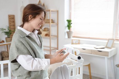 Çocukların yatak odasında bebek monitörü olan genç bir kadın.