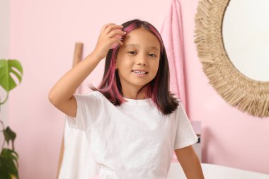 Banyoda aynanın yanında saçlarını tarayan tatlı Asyalı kız.