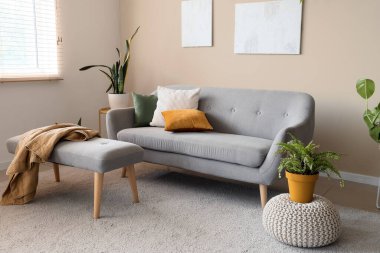 Gri kanepeli, çiçekli ve bej duvarlı şık bir oda.