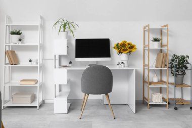 Bilgisayarlı modern çalışma alanı ve hafif ev ofisinde bir buket ayçiçeği.