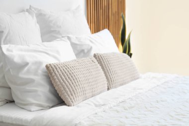 Yatak odasında bir sürü yastığı olan büyük, rahat bir yatak. Yakın çekim.