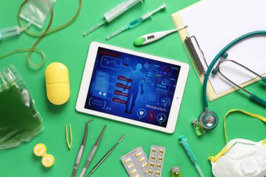 Tablet bilgisayar ve tıbbi malzemeler yeşil arka planda. Teletıp kavramı