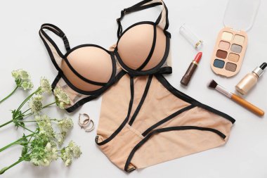 Şık kadın iç çamaşırları, dekoratif kozmetik ürünleri ve açık arkaplanda çiçekler olan kompozisyon