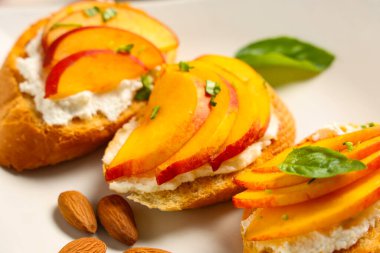 Beyaz arka planda ricotta, fesleğen ve badem fıstıklı şeftali bruschetta, yakın plan.