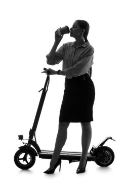 Elektrikli scooterlı iş kadını silueti beyaz arka planda kahve içiyor.
