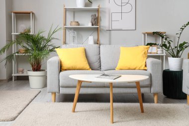 Oturma odasında kanepe, masa ve raf üniteleri var.