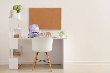 Okul gereçleri, tahta ve sırt çantalı çalışma alanı beyaz duvarın yanında.