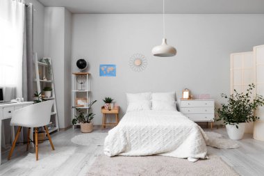 Yatağı, çalışma masası ve raf üniteleri olan hafif ergen odasının içinde.