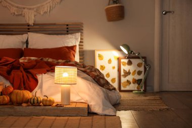 Sonbahar süslemeleri ve akşamları mumları olan şık bir yatak odası.