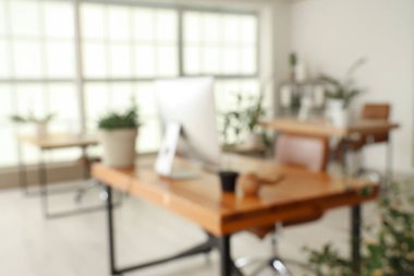 Masalar ve yeşil bitkilerle ofisin bulanık görünümü