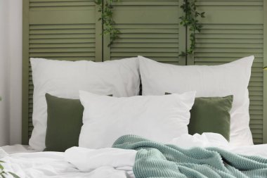 Yatak odasına yastıklı ve dallı rahat bir yatak.