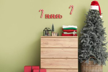 Çekmece, Noel dekoru ve yeşil duvarın yanındaki köknar ağacında kış giysileri yığını.