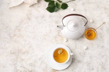 Bir fincan lezzetli ıhlamur çayı ve beyaz grunge arka planda yapraklar.