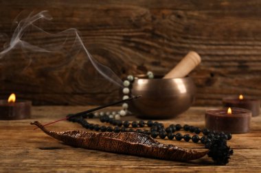 Yanan tütsü, mumlar, boncuklar ve tahta arka planda Tibet şarkı kasesi.