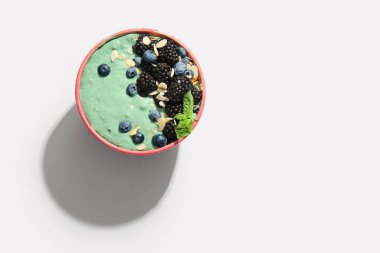 Lezzetli spirulina smoothie ve beyaz arka planda böğürtlenli kase.