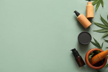 Yeşil arka planda yaprakları olan kenevir kozmetik ürünleri şişeleri ve kavanozu