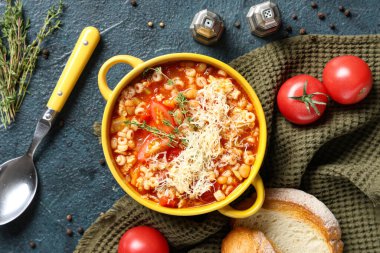 Bir kase peynirli makarna, kekik ve arka planda dilimler.